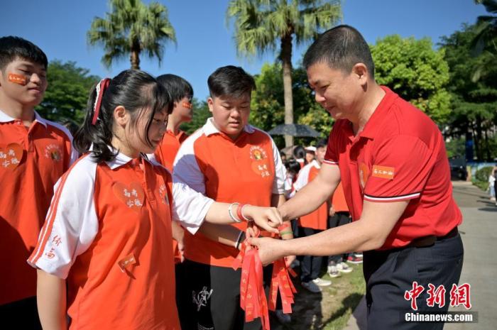 資料圖：廣西華僑實(shí)驗(yàn)高中的教師為高三學(xué)子系上紅絲帶，盼望學(xué)子高考必勝。 俞靖 攝
