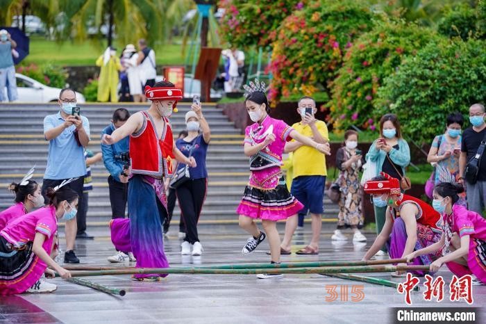資料圖：三亞大小洞天旅游區(qū)入口，工作人員跳竹竿舞迎接游客。 駱云飛 攝
